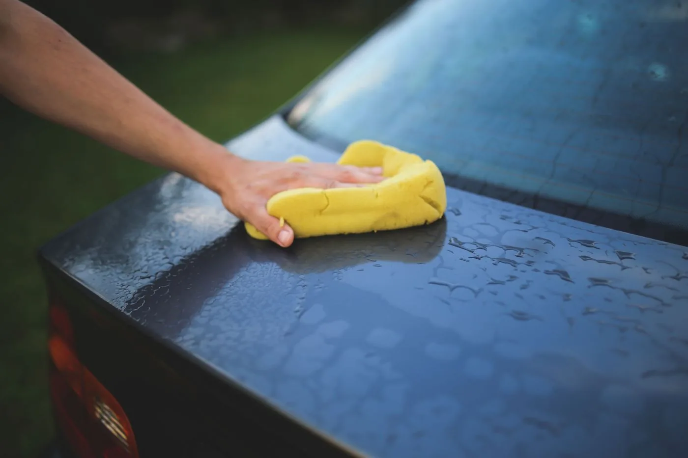 Hand polishing a glossy trunk lid with a sponge